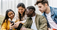 Groupes de 4 jeunes regardant un téléphone en souriant