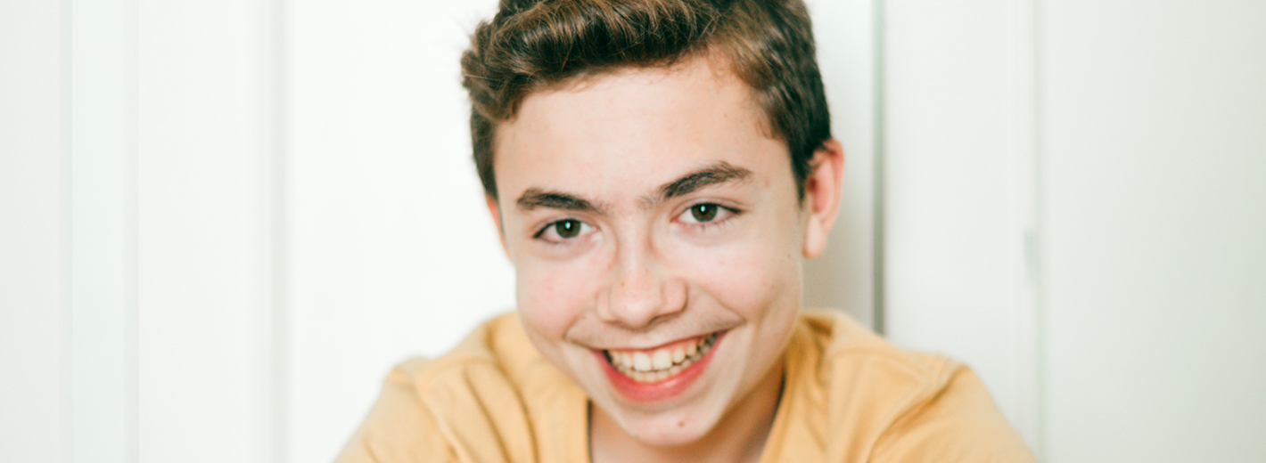 Jeune assis devant un mur, souriant