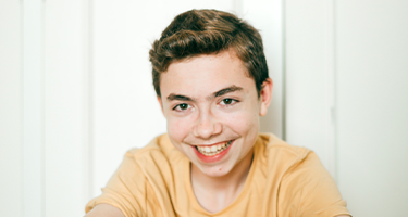 Jeune assis devant un mur, souriant