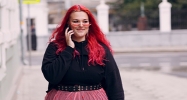 Jeune fille aux cheveux rouges souriant un téléphone à la main